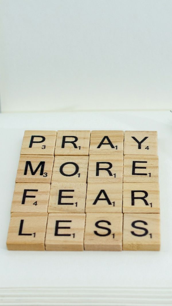 a wooden scrabble that says pray more fear less